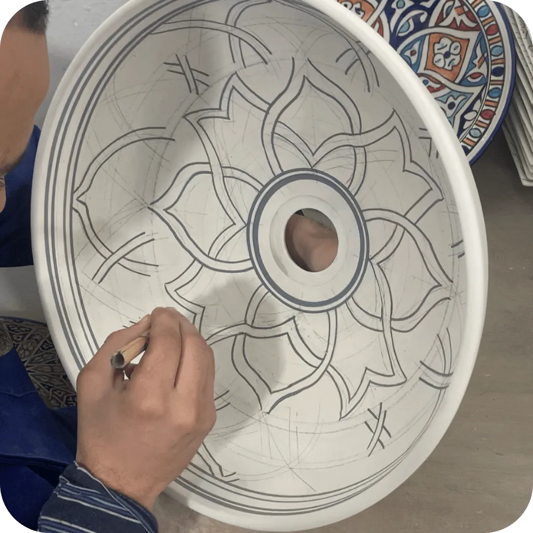 Artisan traçant à main levée le motif d’une vasque en céramique dans l’atelier Mediina à Fès